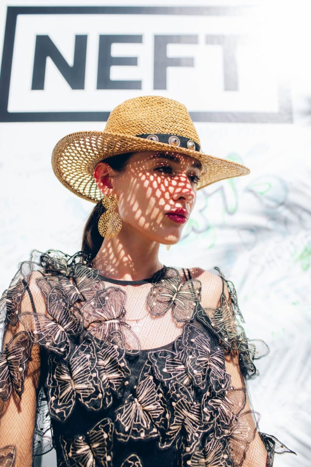 Fashionably dressed woman wearing a lace dress and straw hat, captured in stylish outdoor portrait