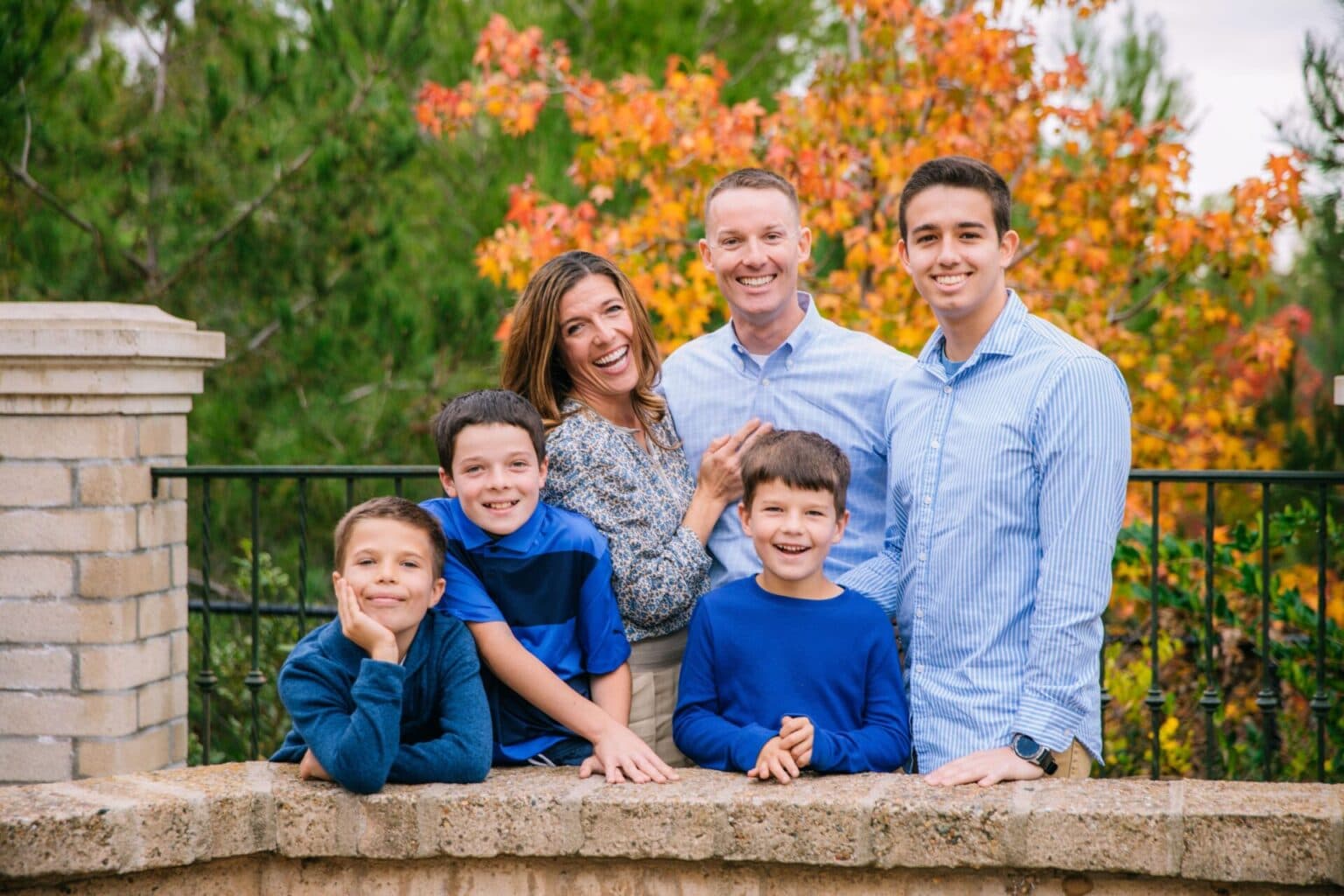 Family portrait outdoors with parents and kids on a stone ledge.