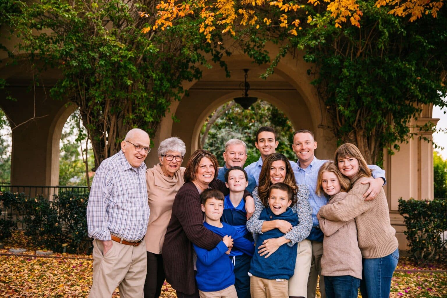 Large multigenerational family group portrait outdoors, smiling together.