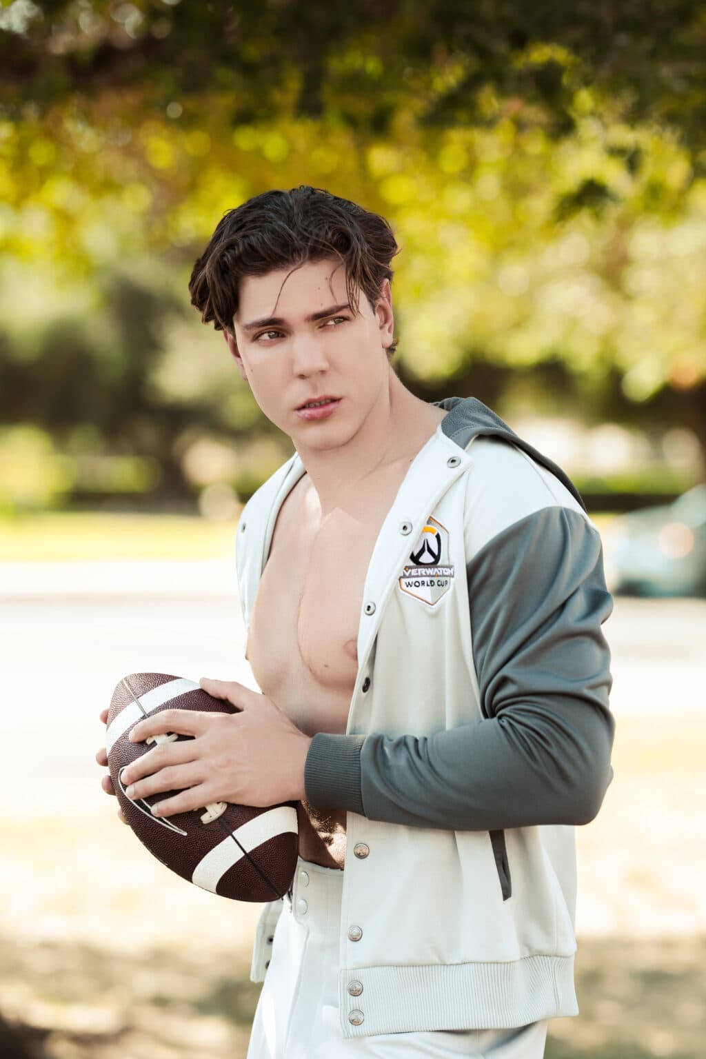 Young man shirtless with football, outdoors, casual headshot for acting or sports agency.