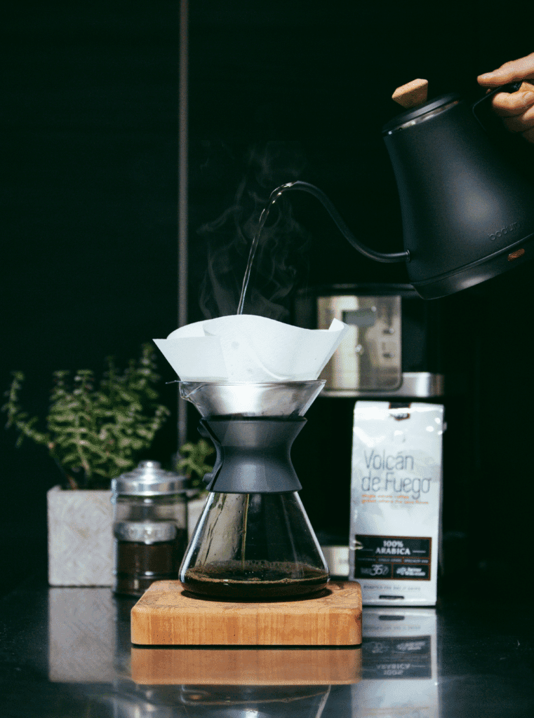 Pour-over coffee setup with kettle and filter on dark counter.