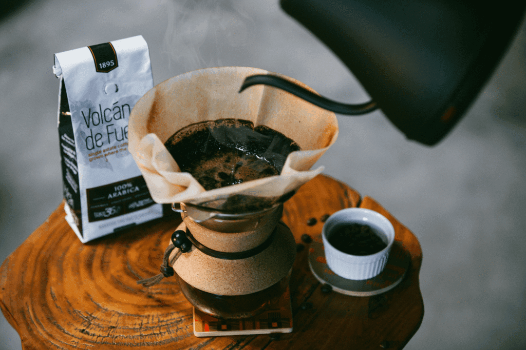 Pour-over coffee setup with grinder, filter, and bag on wooden table.