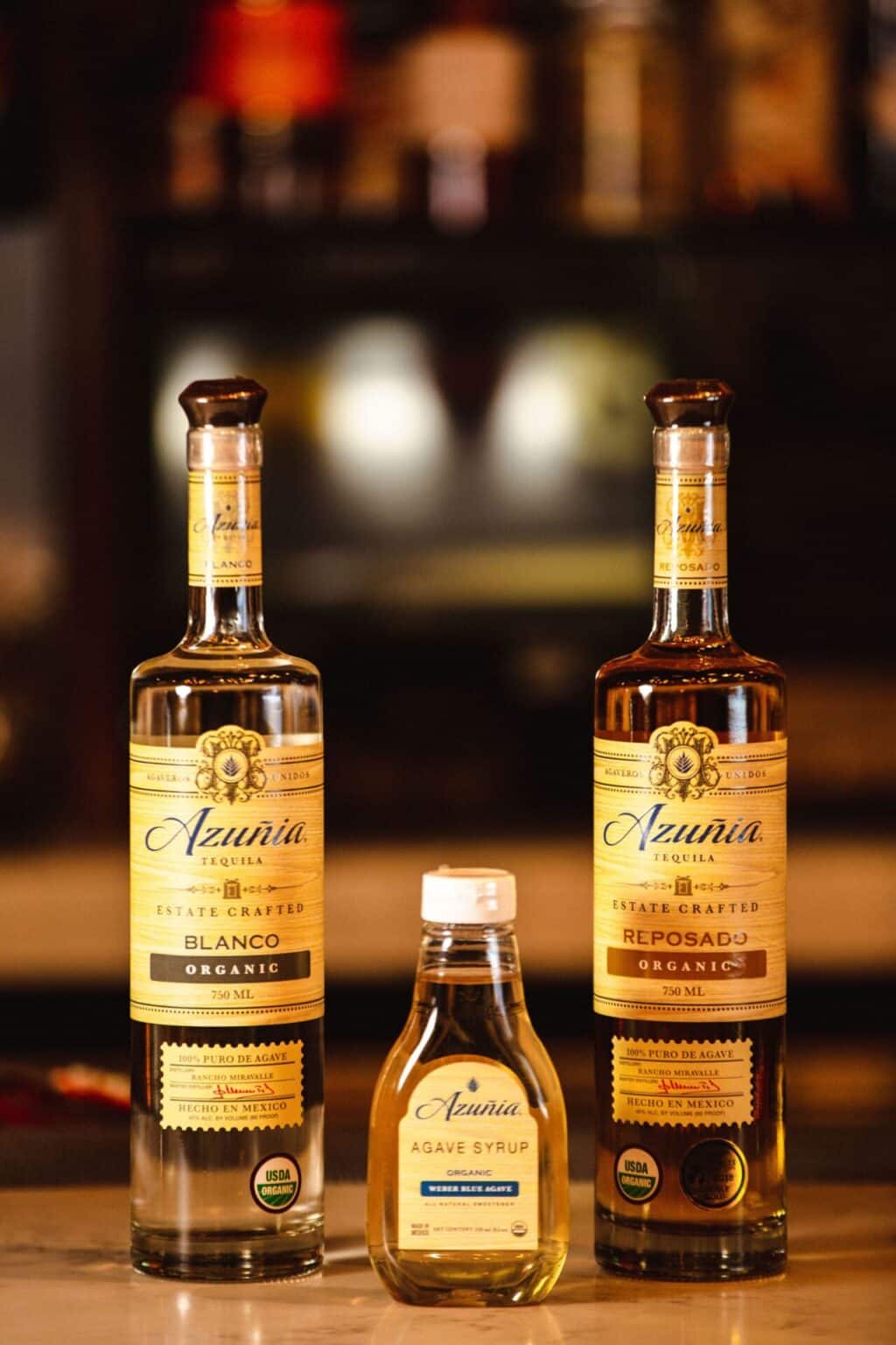 Tequila bottles and agave syrup on bar counter, culinary photography.