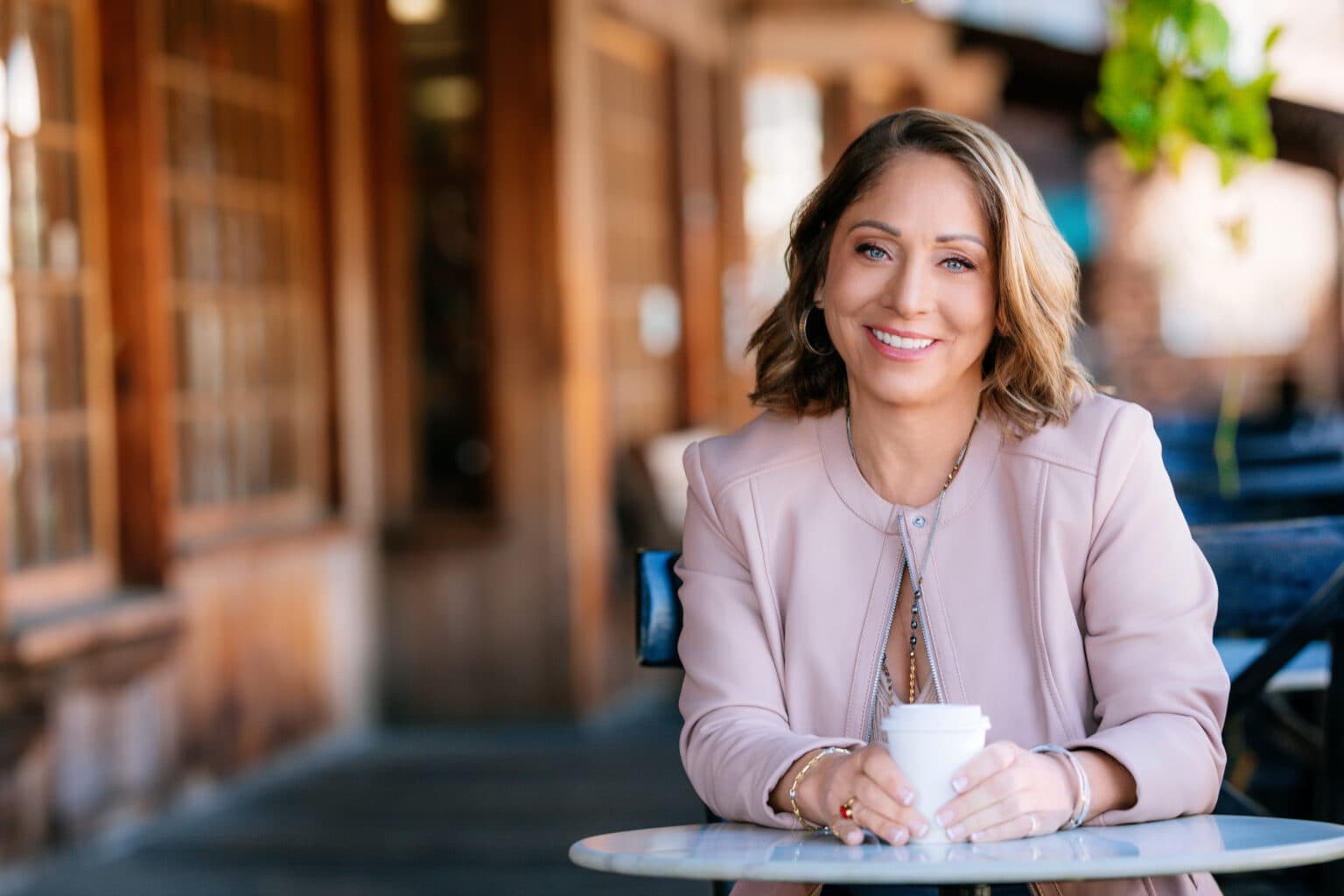 Professional headshot of a smiling woman in a light blazer photographed in an office